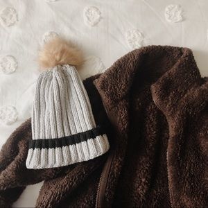 gray and black beanie with brown / tan pom pom